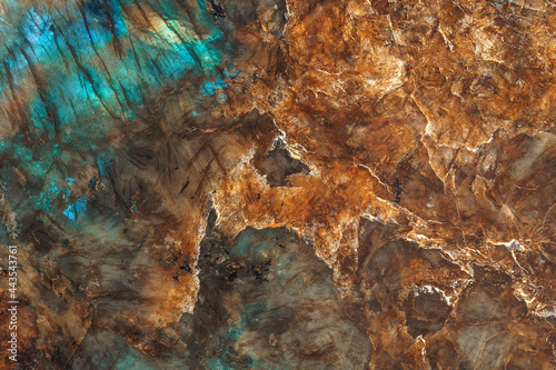 The texture of a mineral stone of labradorite or granite, shimmering with different colors, is close-up.