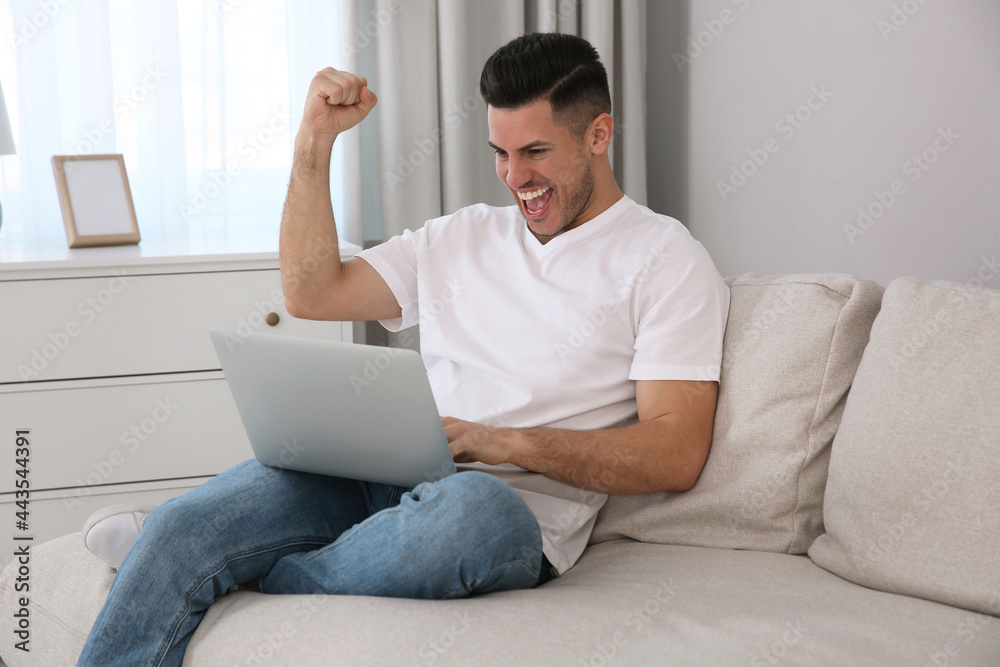 Emotional man participating in online auction using laptop at home Emotional man participating in online auction using laptop at home