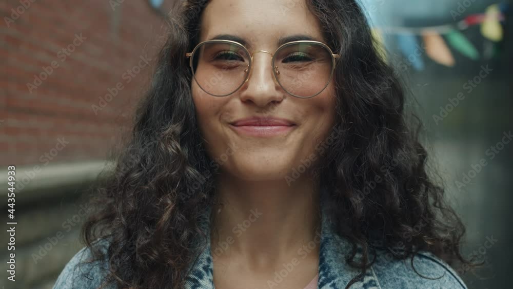 Close-up portrait of cute mixed race woman in glasses smiling and laughing outside in city street. Positive emotions and joyful youth concept. Close-up portrait of cute mixed race woman in glasses smiling and laughing outside in city street. Positive emotions and joyful youth concept.