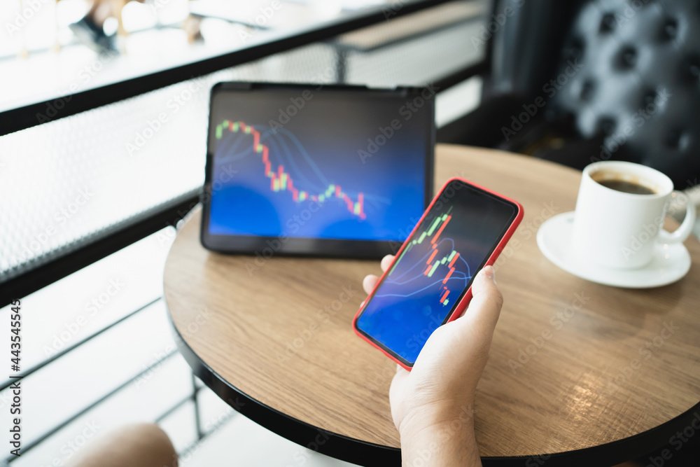 Fototapeta premium Man holding phone and looking at candlestick chart suitable for Stock market forex or cryptography trading financial investment graphs Finance Economy trends Trading Stock Concept