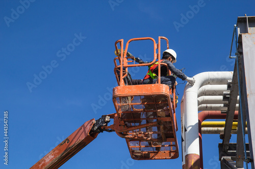 Male workers in a boom lift of thickness pipeline oil