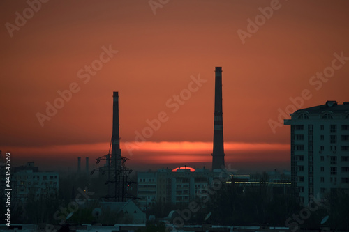 Urban landscape with houses and factory chimneys at sunset the sky is pink