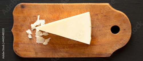 Tableau sur toile Pecorino Romano Cheese on a rustic wooden board on a black surface, top view