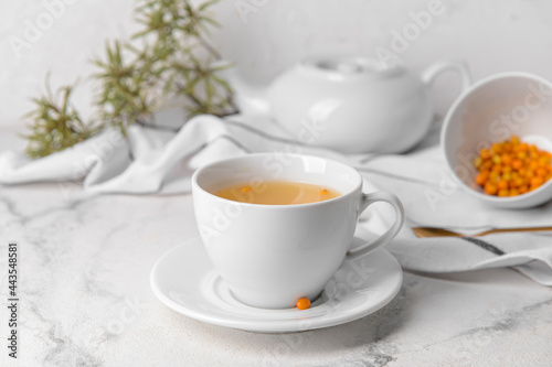 Cup of healthy sea buckthorn tea on table