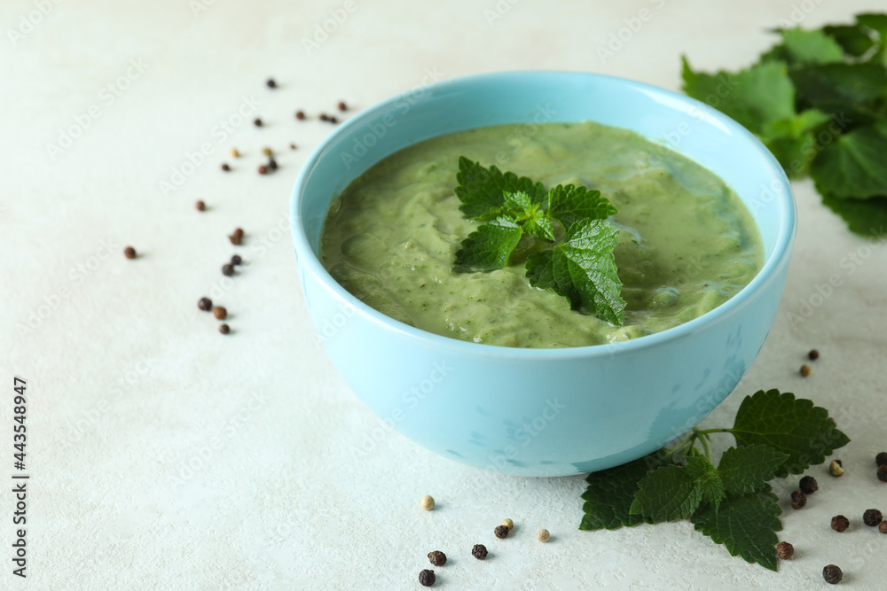 Concept of healthy food with nettle soup on white textured table Concept of healthy food with nettle soup on white textured table