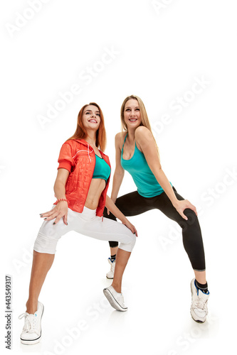 Full photo of two beautiful athletic sporty girls training together on white background