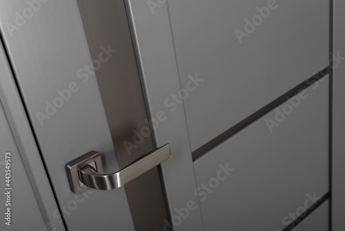 Closeup photo of chrome handle on gray door with frames