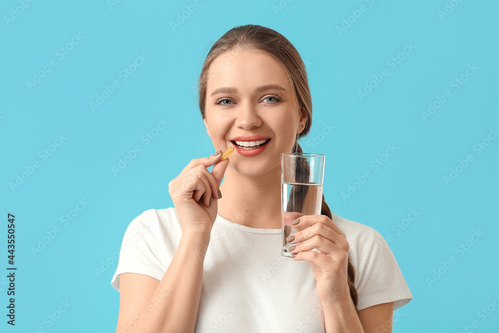 Young woman taking fish oil on color background Young woman taking fish oil on color background