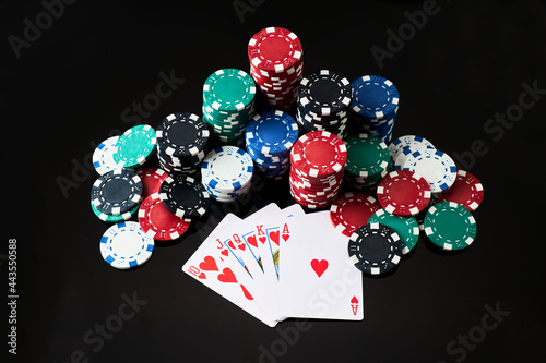 Stack of Casino gambling chips and cards isolated on black reflective background