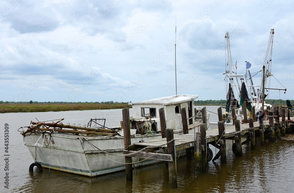 an old fishing boat docked at the wooden pier on the altamaha river in darien , georgia, on a stormy day an old fishing boat docked at the wooden pier on the altamaha river in darien , georgia, on a stormy day