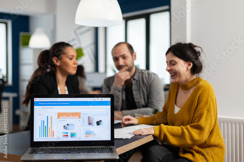 Business woman talking about financial project, taking notes, discussing start up ideas using laptop. Diverse employees gathered in co-working, working process in busy company, teamwork help concept