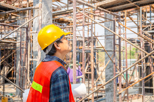 Worker man in hard hat holding blueprint checking and planning project at construction site