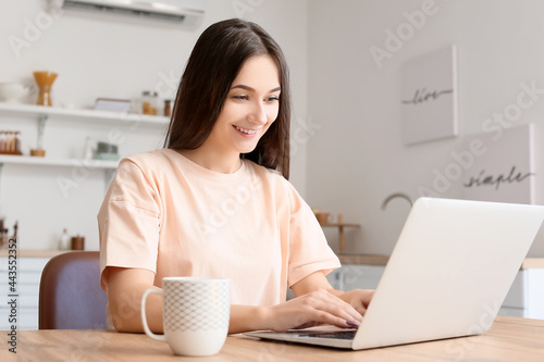 Young woman using laptop in kitchen