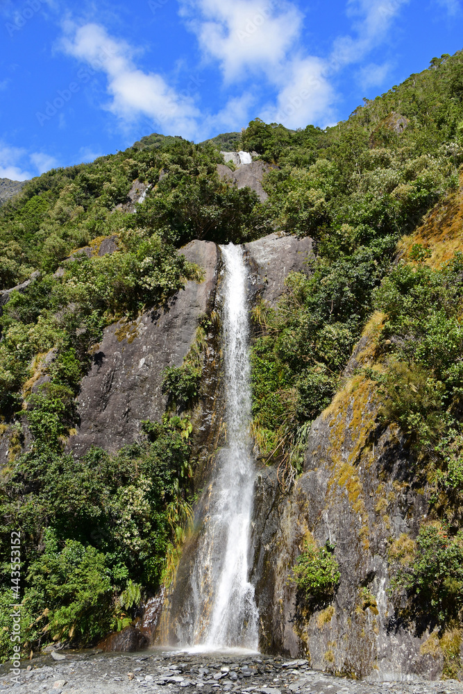 beautiful trident creek waterfalls on a sunny summer  along the franz joseph glacier  walk,  near the town   of franz joseph on the west coast of the south island of new zealand