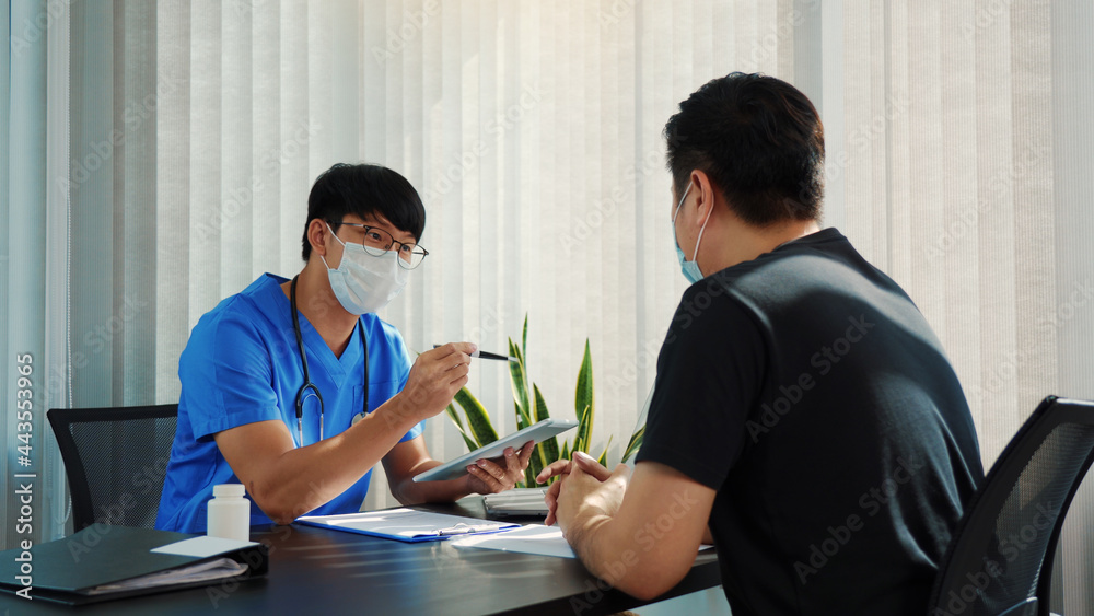 Doctors are explaining the treatment of a sick patient in tablets while wearing a mask during the virus outbreak. Doctors are explaining the treatment of a sick patient in tablets while wearing a mask during the virus outbreak.