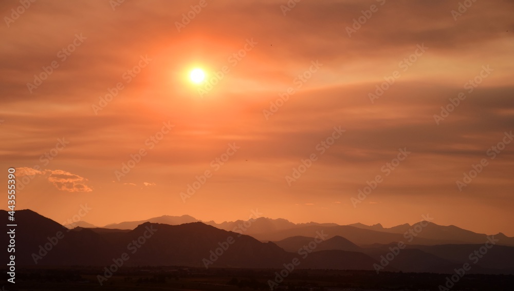 fiery sunset over the front range of the colorado mountains due to the smoke from  the western forest fires, as seen from broomfield, colorado