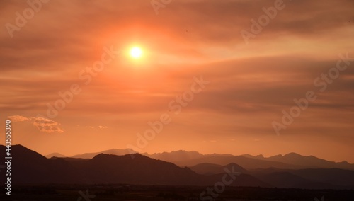 fiery sunset over the front range of the colorado mountains due to the smoke from the western forest fires, as seen from broomfield, colorado