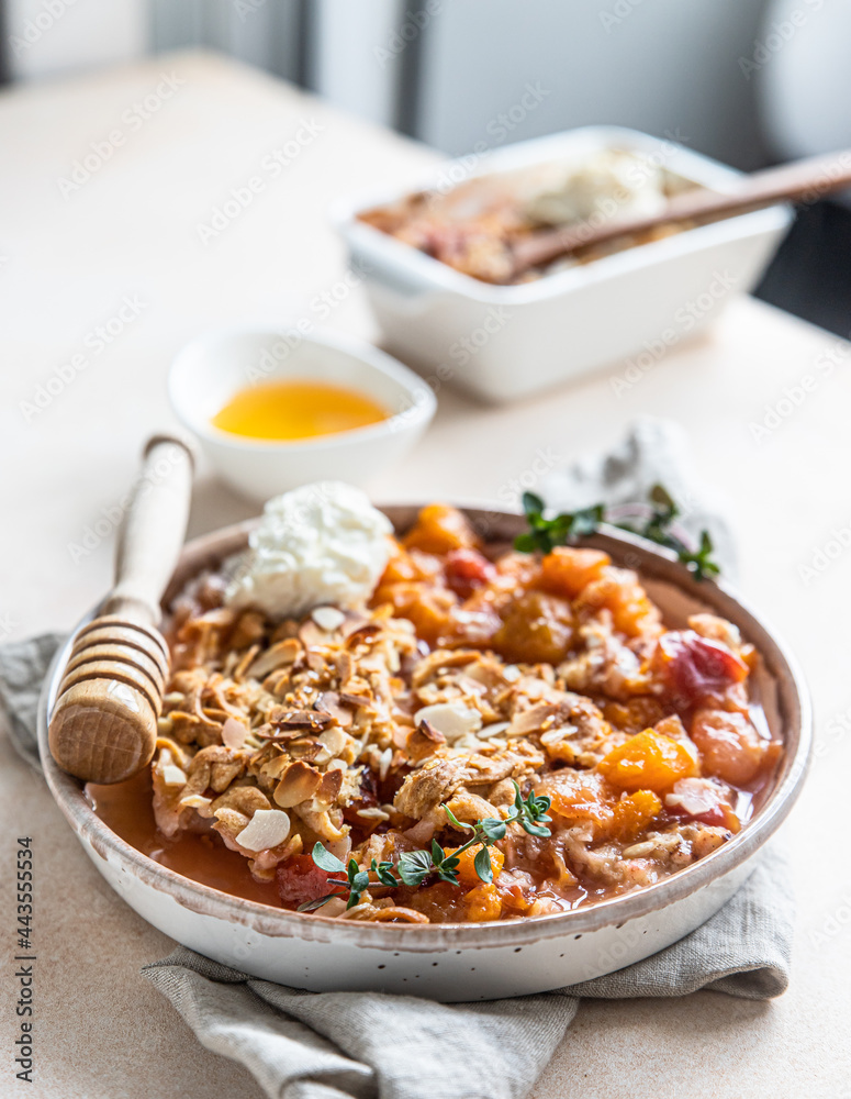 Ceramic plate with tasty plum crumble dessert served with vanilla ice cream and herbs.