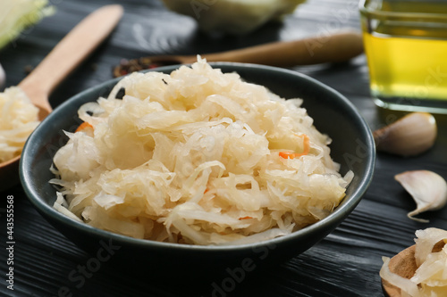 Bowl with tasty sauerkraut on dark wooden background, closeup