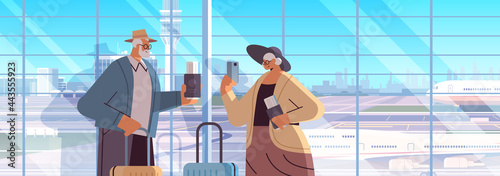 elderly couple of tourists grandparents with luggage passports and tickets ready to boarding at airport vacation traveling