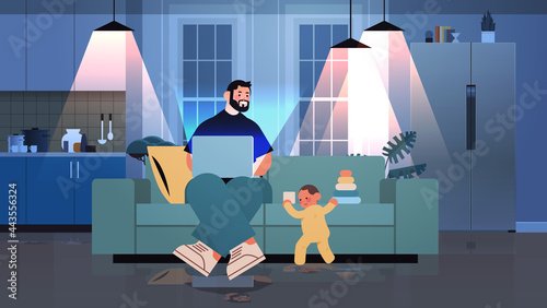busy father freelancer working at home using laptop little son playing with toys freelance fatherhood concept
