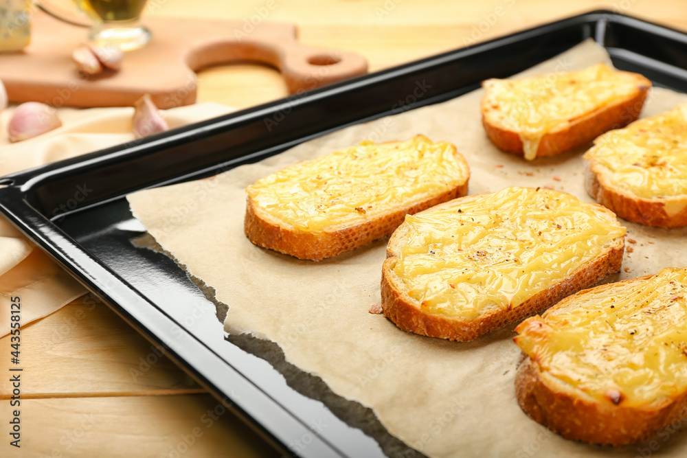 Baking sheet with tasty toasts on wooden background