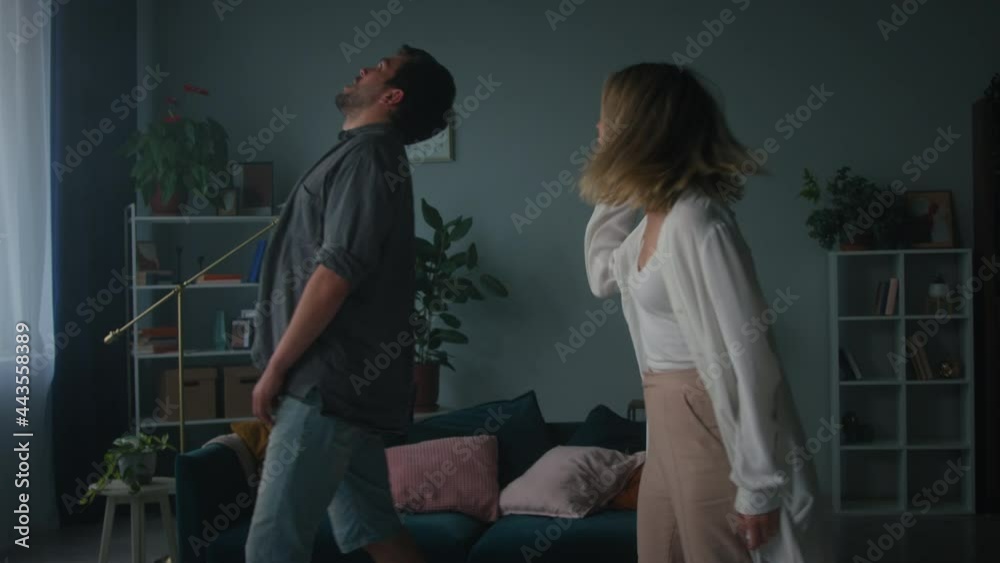 Aggressive wife screaming at husband, fighting, couple quarreling in the evening at home man and woman shouting at each other, gesturing. Scandal and crisis in family. Domestic violence, abuse.