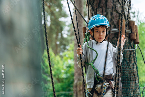 Active, little boy in a protective helmet crosses obstacles on a cable car. The child actively spends time