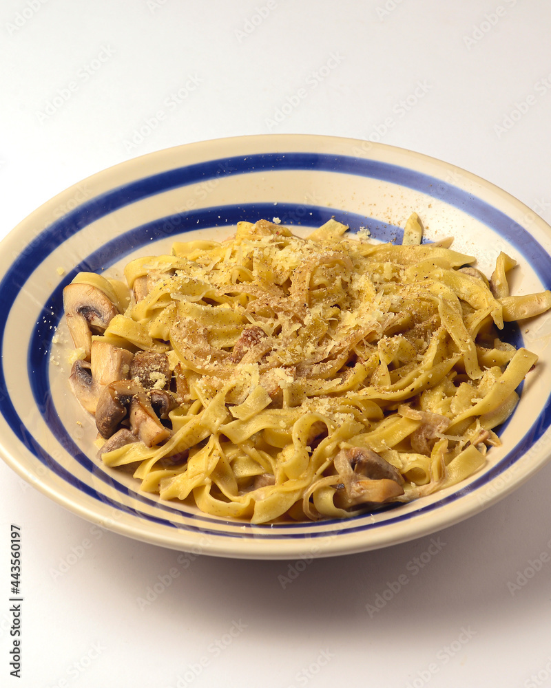 Pasta Penne with chicken and mushroom under parmesan cheese served on a plate over white background