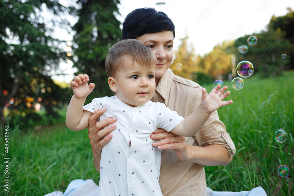 Little boy catches soap bubbles with his hands on a green lawn Little boy catches soap bubbles with his hands on a green lawn