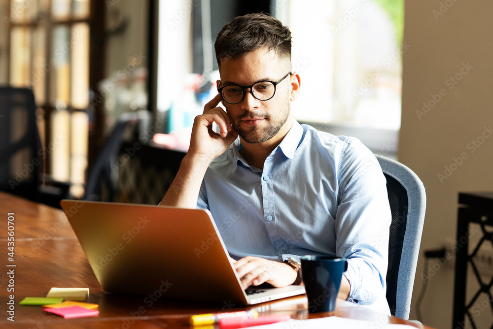 Young businessman using laptop in his office. Handsome man working on laptop. Young businessman using laptop in his office. Handsome man working on laptop.