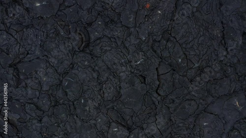 Dark black basalt rock solidified lava field cracked rugged surface photo