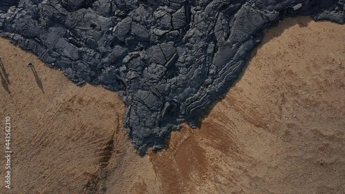 Edge of black basalt lava field with cracked surface rock, Iceland photo