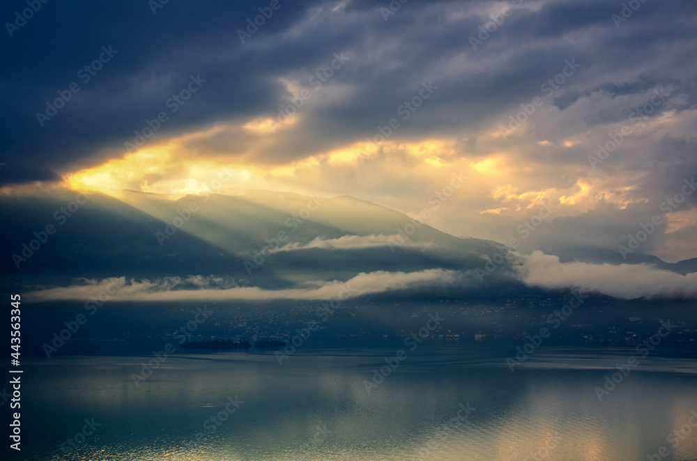 Storm Clouds with Sunlight over Brissago Islands on Alpine Lake Maggiore with Mountain in Ticino, Switzerland.