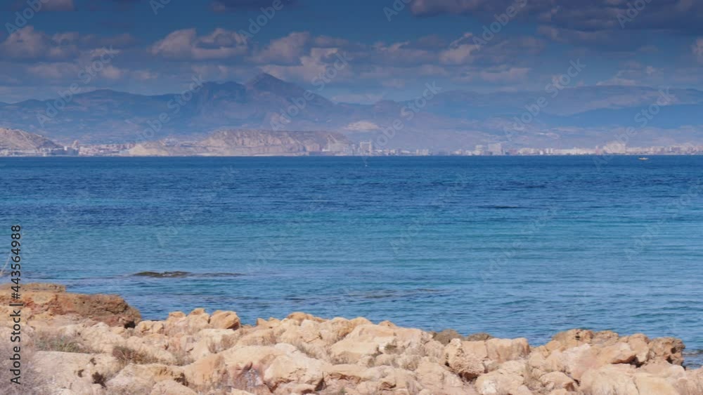 Seaside landscape. Spanish beach rocky sea shore. Mediterranean Sea. Alicante coast in the distance. Seaside landscape. Spanish beach rocky sea shore. Mediterranean Sea. Alicante coast in the distance.