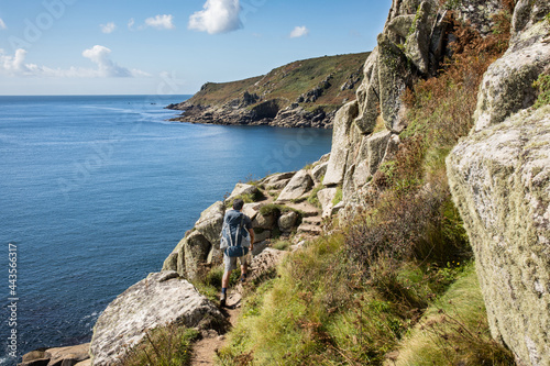 Hiker tackles some big stone steps on south west coast path near Lamorna Cove beach, Penzer point in Cornwall