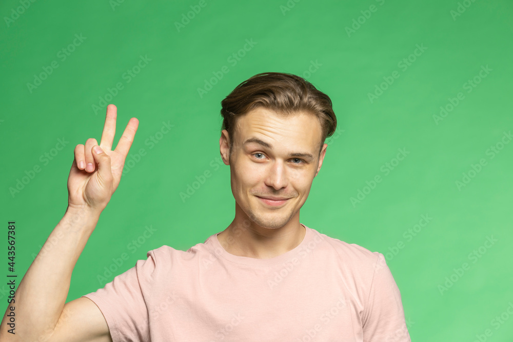 Portrait confident young man gesturing peace sign on green background
Portrait confident young man gesturing peace sign on green background