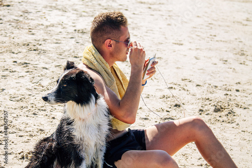 relaxed man on the beach with his pet listening to music with mobile phone headphones photo