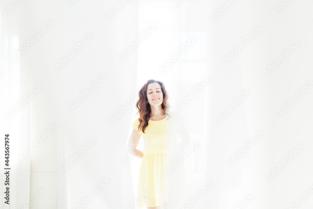 portrait of a beautiful brunette woman in a yellow summer dress by the window portrait of a beautiful brunette woman in a yellow summer dress by the window