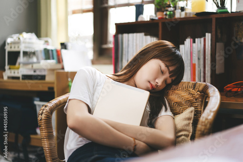 Asian teenager student woman hold digital tablet and take a sitting nap on chair stay at home. photo