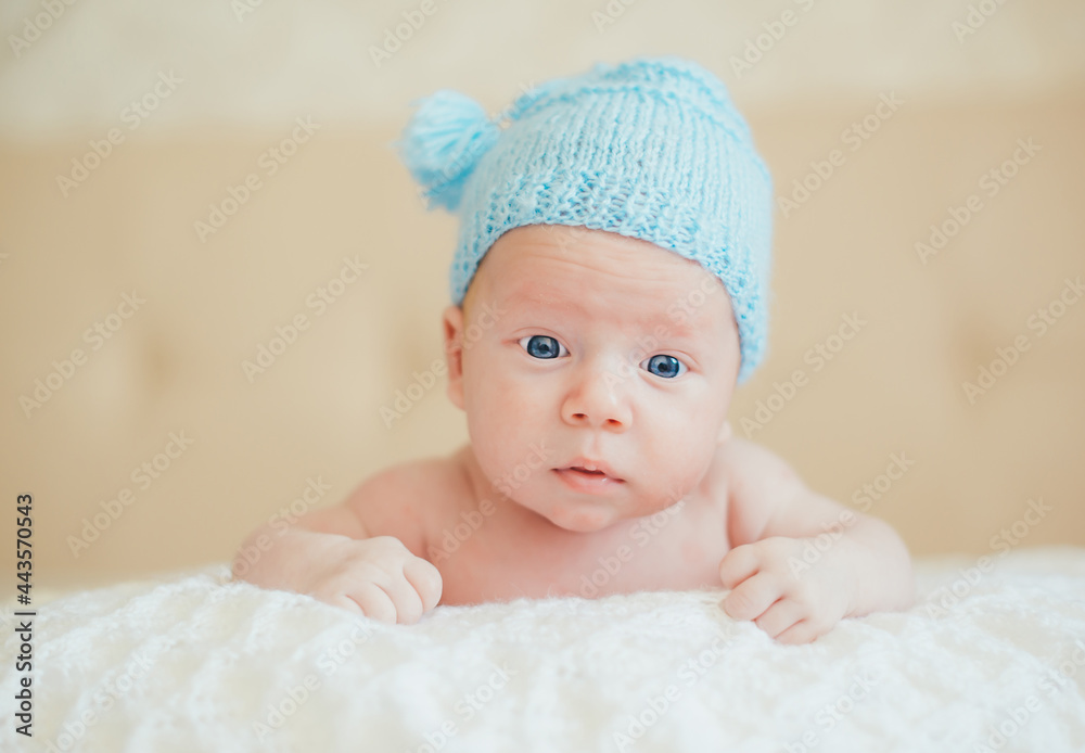 A kid in a knitted blue cap lies on his stomach, raised his head and looks in surprise. A kid in a knitted blue cap lies on his stomach, raised his head and looks in surprise.