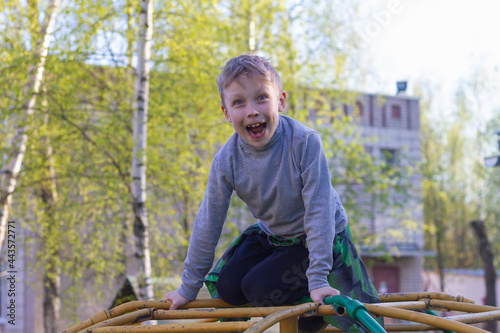 A preschool boy climbs metal ladders on a playground in the spring