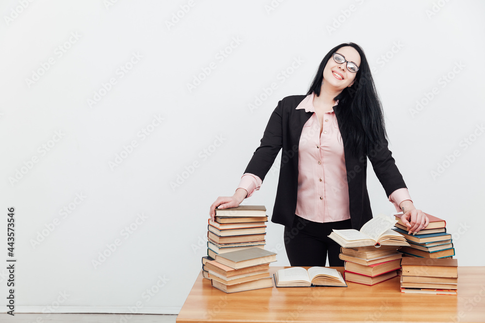 beautiful female teacher in business suit at a table with stacks of educational books beautiful female teacher in business suit at a table with stacks of educational books
