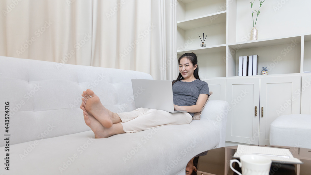 Asian woman sitting on sofa and using laptop to shop online with credit card to register for payment or online transactions, Financial transactions and Internet security, Shopping with credit card. Asian woman sitting on sofa and using laptop to shop online with credit card to register for payment or online transactions, Financial transactions and Internet security, Shopping with credit card.