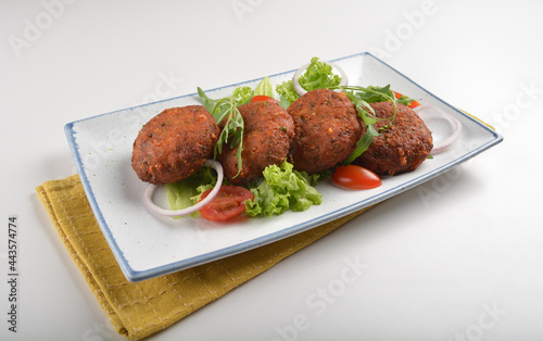 deep fried golden potato cake ball with greens salad in white background asian Indian appetiser halal menu