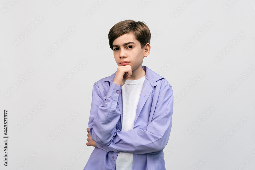Portrait of a pretty boy 12-14 years old holding hand on his chin, staring at camera with thoughtful mysterious look Portrait of a pretty boy 12-14 years old holding hand on his chin, staring at camera with thoughtful mysterious look