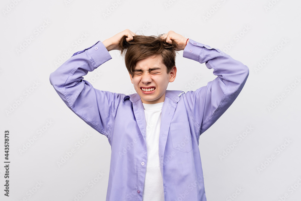 Frustrated boy with eyes closed, messing up and pulling his hair, hands to head shouting and screaming Frustrated boy with eyes closed, messing up and pulling his hair, hands to head shouting and screaming