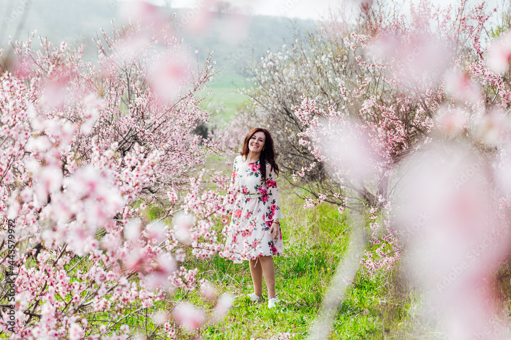 Beautiful woman in a dress with flowers walks through the flowering garden in spring Beautiful woman in a dress with flowers walks through the flowering garden in spring