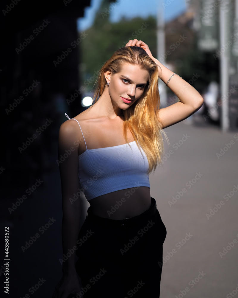 Fototapeta premium Blonde outdoors in white top, black pants and heels