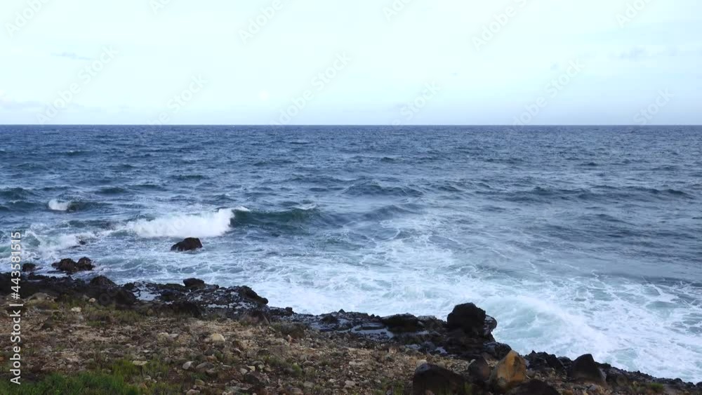 The ocean waves breaking on the rocks along the seashore casting spray into the air. The ocean waves breaking on the rocks along the seashore casting spray into the air.